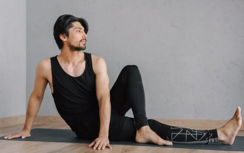 A man in athletic wear practicing yoga indoors, focusing on stretching and mindfulness.