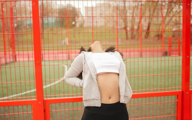A young woman stretches outdoors in a vibrant urban park, focusing on fitness and wellness.