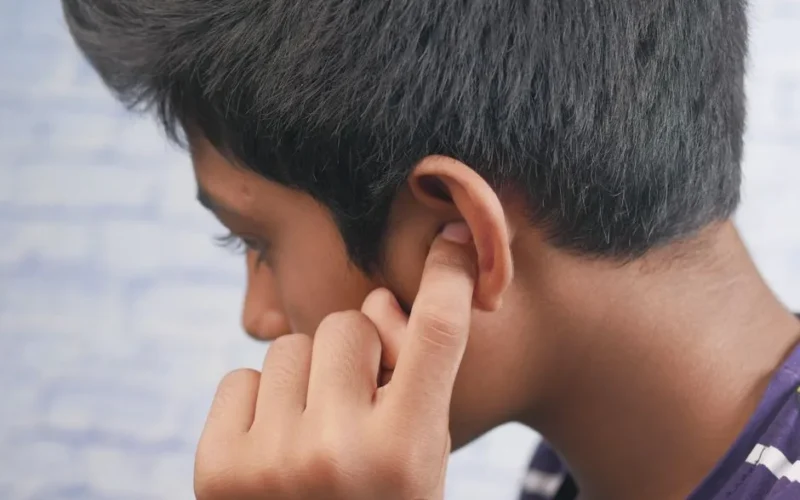 Close-up of a teenager's profile with hand covering ear, reflecting introspection or concentration.
