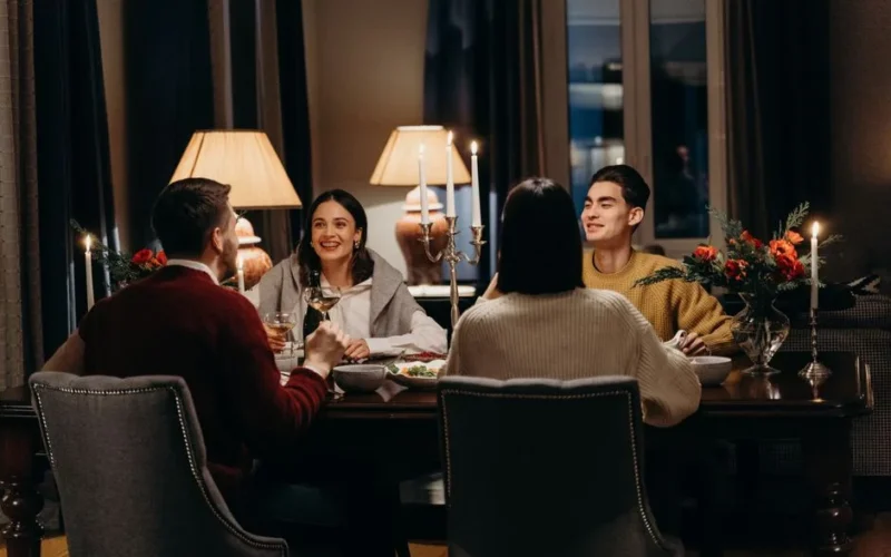 Warm indoor dinner scene with friends enjoying food and conversation.