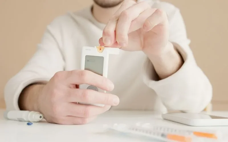 Close-up of a person checking blood sugar with a glucose meter at home.