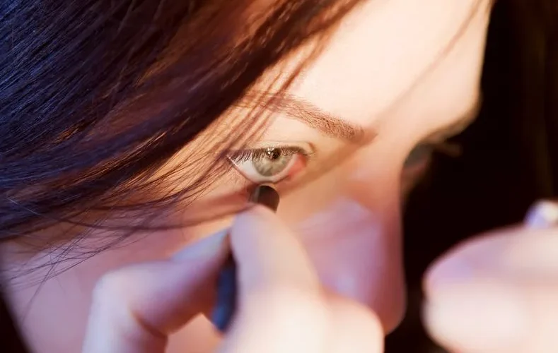 Close-up view of a woman precisely applying eyeliner with focus.