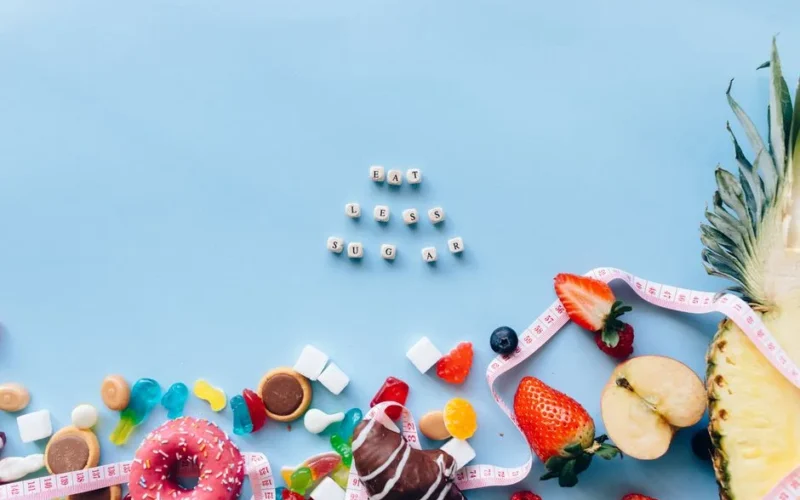 Juxtaposition of sugary sweets and fresh fruits with a message to eat less sugar.