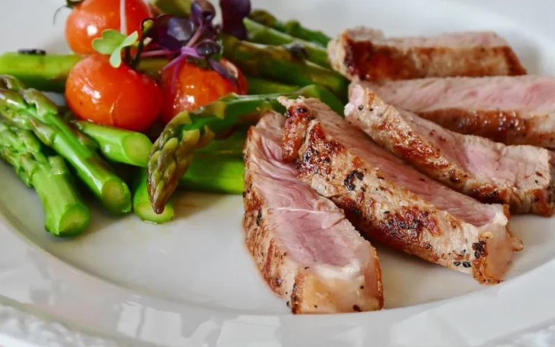 Close-up of grilled steak slices with asparagus and cherry tomatoes, perfect for a healthy meal.