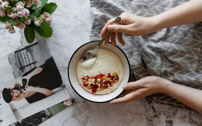 A warm breakfast setup featuring a bowl of porridge with fruit and nuts, perfect for a cozy morning.