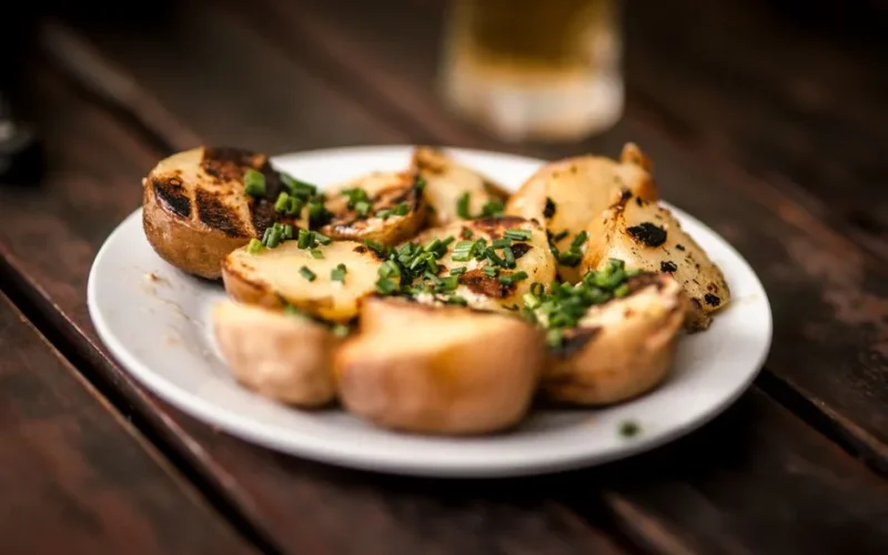 Delicious grilled potatoes garnished with fresh chives, perfect for a rustic meal.