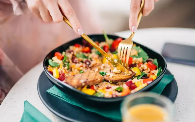 Vibrant quinoa salad with fresh veggies being enjoyed by a diner.