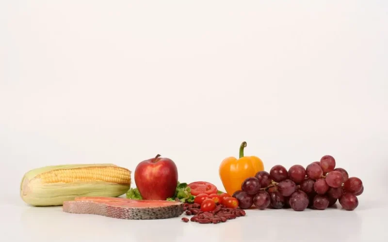 Vibrant display of fruits, vegetables, and salmon on a white background, ideal for food and health themes.