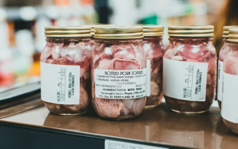 Detailed close-up shot of bottled pork tongues on display in a supermarket.