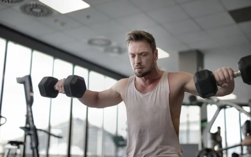Focused man working out with dumbbells at gym showcasing strength and determination
