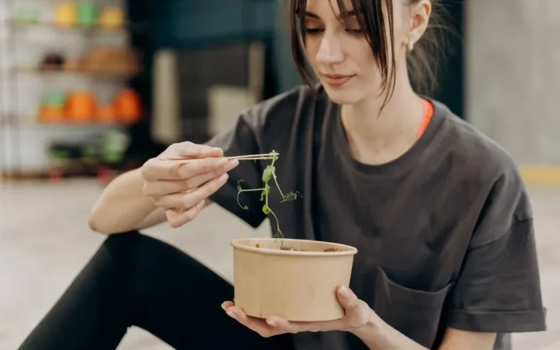 Young woman enjoying a healthy salad indoors, focusing on balanced nutrition and healthy living.