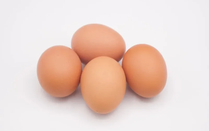 A close-up of fresh brown eggs on a white background, highlighting their natural texture.