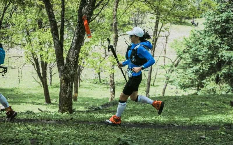 Athlete running on forest trail during a marathon race, surrounded by nature.