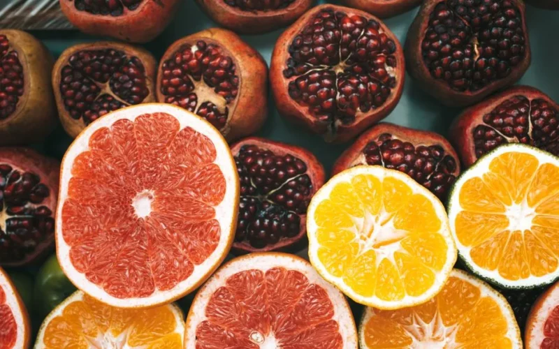 Close-up view of colorful sliced citrus fruits and pomegranates showcasing freshness and nutrition.
