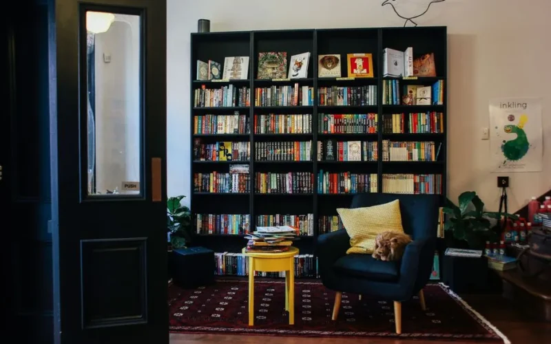 A warm and inviting home library featuring a bookshelf, cozy armchair, and decorative accents.