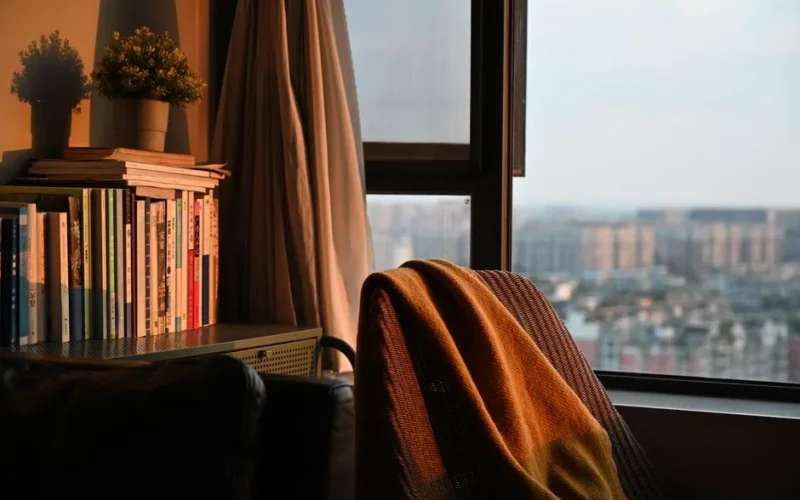 Warm and inviting indoor corner with books and sunset view, perfect for relaxing.