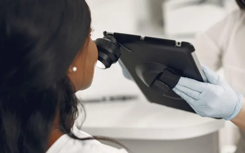 Dermatologist examining a patient's skin using a digital dermatoscope and tablet for precision observation.