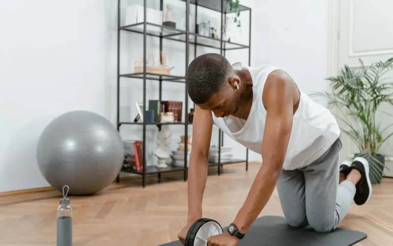 Adult male using an ab wheel for exercise in a home gym setting, focusing on fitness.