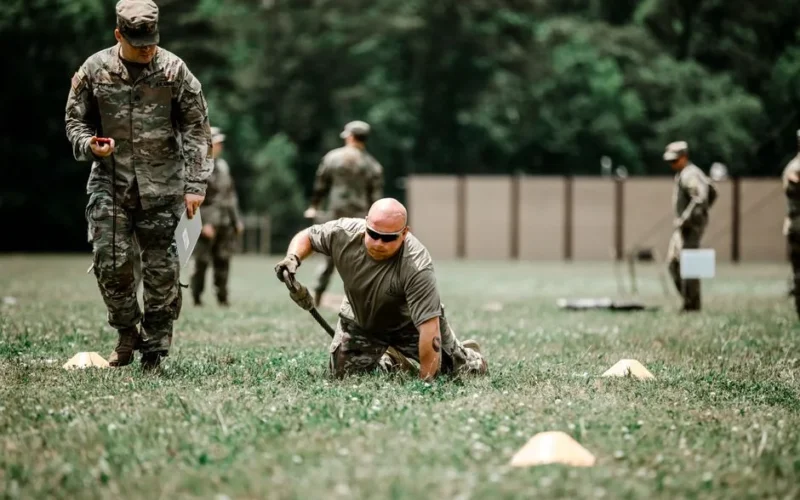 A group of soldiers engaged in a rigorous outdoor military training session in a grassy field.