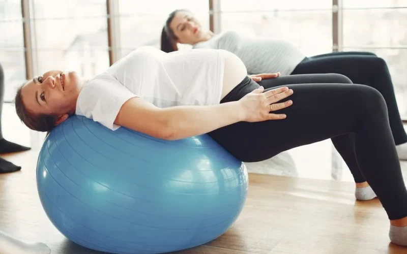 Pregnant women engaging in low-impact exercise with fitness balls indoors.