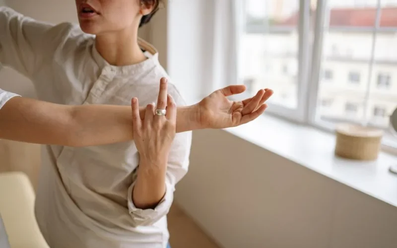 Physical therapist stretches a woman's arm in a sunny room.