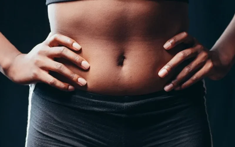 A close-up shot of hands on an athletic abdomen, symbolizing fitness and health.