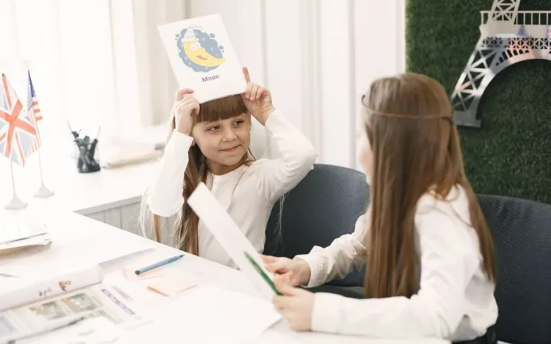 Two young girls interacting during an educational activity with playful learning in a classroom setting.