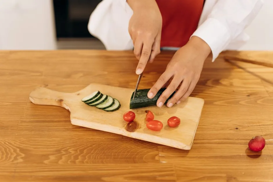 A woman slices cucumbers and cherry tomatoes for a healthy salad in a modern kitchen.