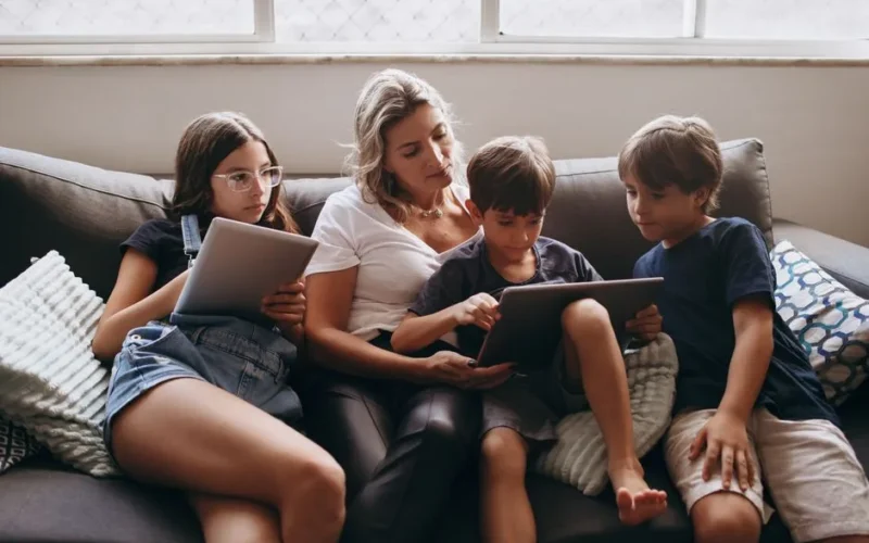 A family enjoying a relaxing time together on a sofa, using tablets.
