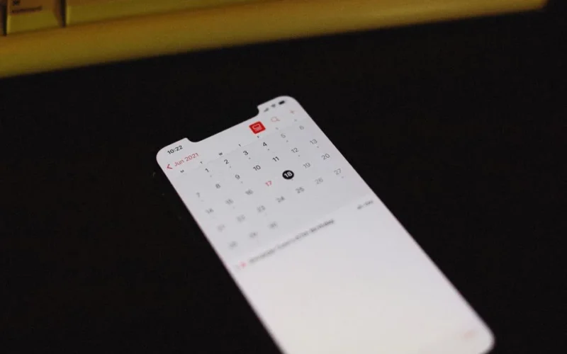 Smartphone with illuminated calendar app screen on a dark background, June 2021 visible.