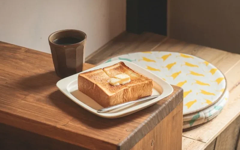 A cozy breakfast setting featuring buttered toast and a cup of coffee on a wooden table.