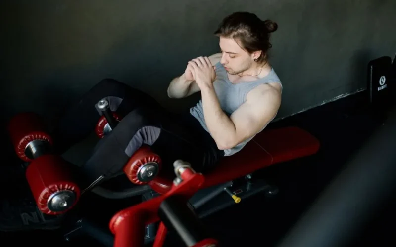 A focused man performs abdominal exercises on gym equipment, highlighting fitness and determination.