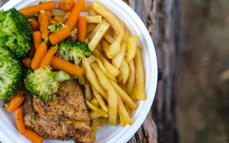 Delicious chicken dinner with broccoli, carrots, and fries on a plate.