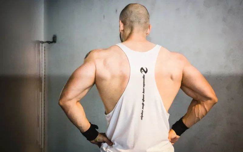 A muscular man from behind showcasing strength and fitness in a gym setting.