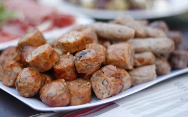 Close-up of cooked sliced sausages on a white plate, tempting and delicious.