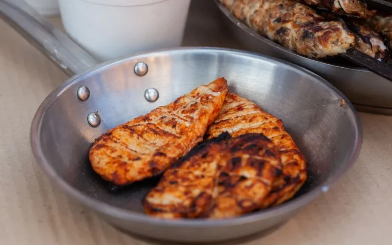 Delicious seasoned chicken breasts grilled and served in a stainless steel pan.