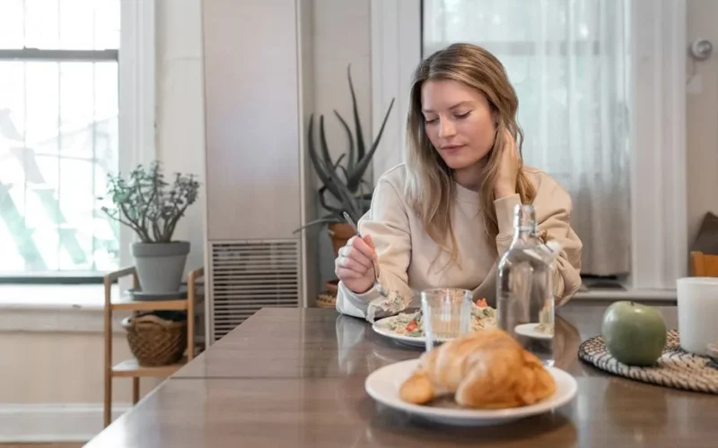 A woman indulging in a healthy salad at a cozy indoor setting, promoting wellness.