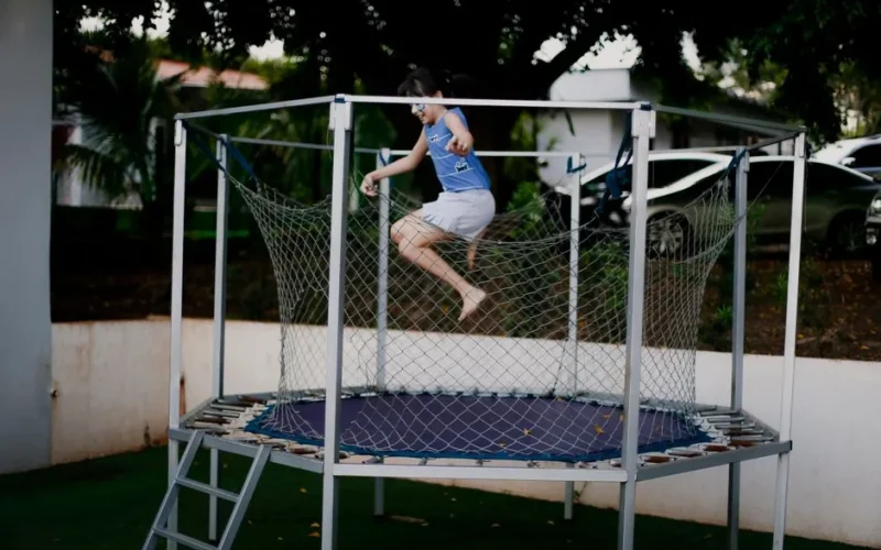 A young girl energetically jumps on a trampoline outdoors, enjoying a fun and playful moment.