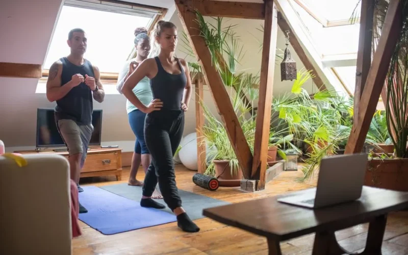 Group of adults participating in a fitness session in a cozy loft apartment with natural light.