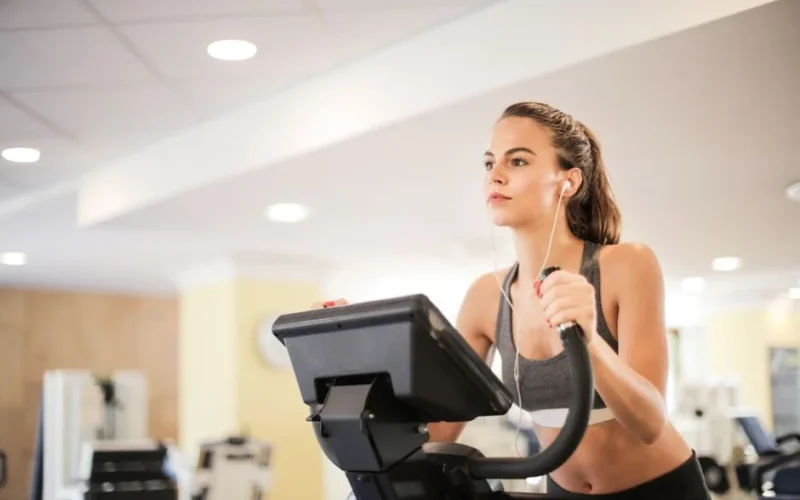 Woman in a gym focused on cardio exercise using elliptical machine. Healthy lifestyle and fitness concept.