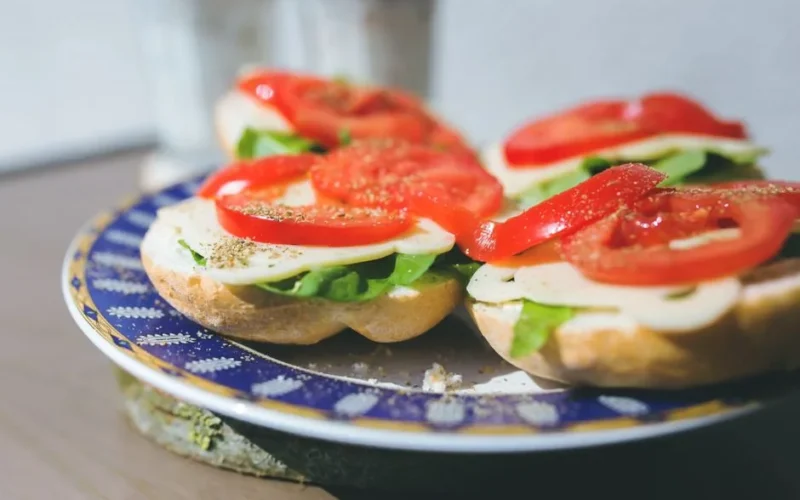 Close-up of vegetarian sandwiches with cheese, lettuce, and tomato on a decorative plate.
