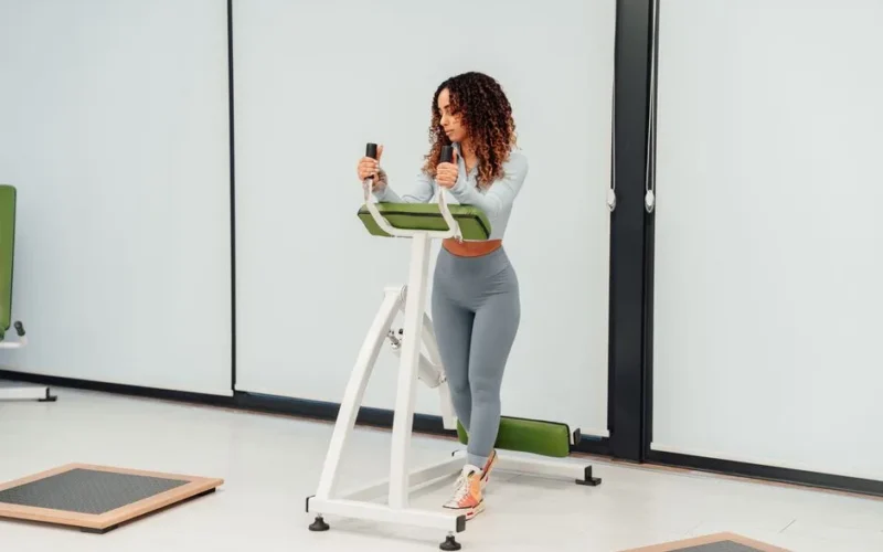 A young woman exercises on fitness equipment in a modern indoor gym setting, embracing a healthy lifestyle.