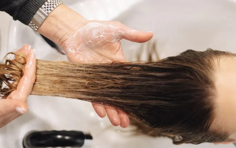 Close-up of a professional hair wash in a salon setting, highlighting hand technique.