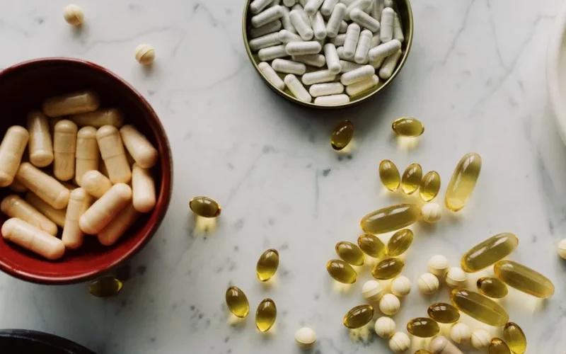 From above of biologically active additives and pills during sorting in different containers on the table in the hospital