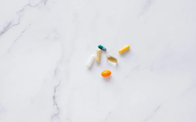 A variety of colorful pills arranged on a white marble surface, representing healthcare.