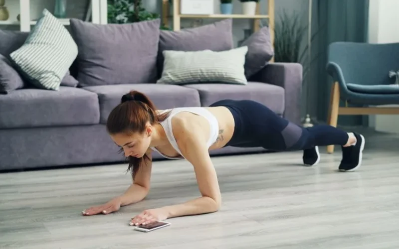A woman performing a plank exercise in a modern living room setting.