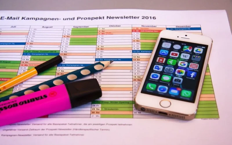 A desk setup featuring a planner, pens, and a smartphone displaying app icons, ideal for productivity.