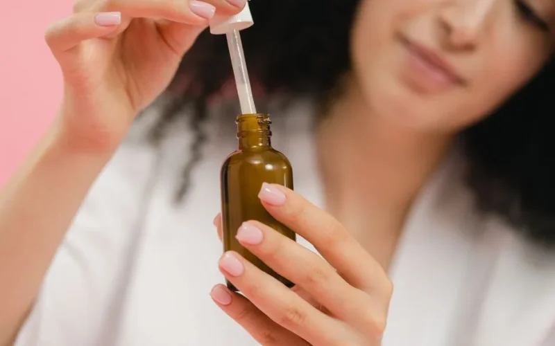 Close-up of a woman using a dropper bottle, focusing on skincare and beauty routine.