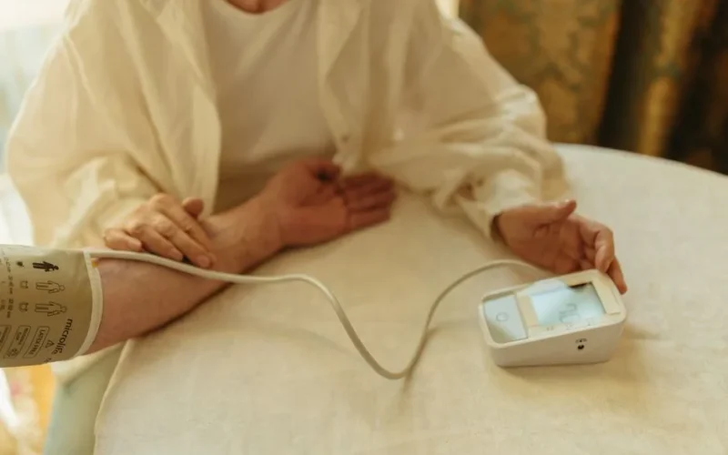A senior adult checking their blood pressure with a digital monitor at home.