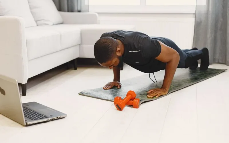 A man doing push-ups on a mat in a modern living room, focusing on home workouts.